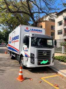 Caminhão baú da Leandro Mudanças e Transportes estacionado em área residencial, ilustrando a importância de filmar cômodos para orçamento de mudança.